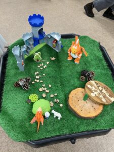 Toys used to re-enact the story in Julia Donaldson's picture book "Zog", including an orange dragon representing the character of Zog, a toy castle, toy sheep, and toy trees.